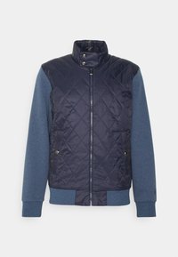 Marineblauw gewatteerd donsjack met blauwe lange mouwen, hoge kraag, ritssluiting en voorzakken, met een gladde textuur en geribde manchetten.