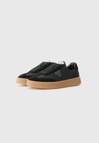 Sorte joggesko laget av en blanding av semsket skinn og syntetisk materiale, med gummiråsole, snørebånddesign og et logoakzent på siden.