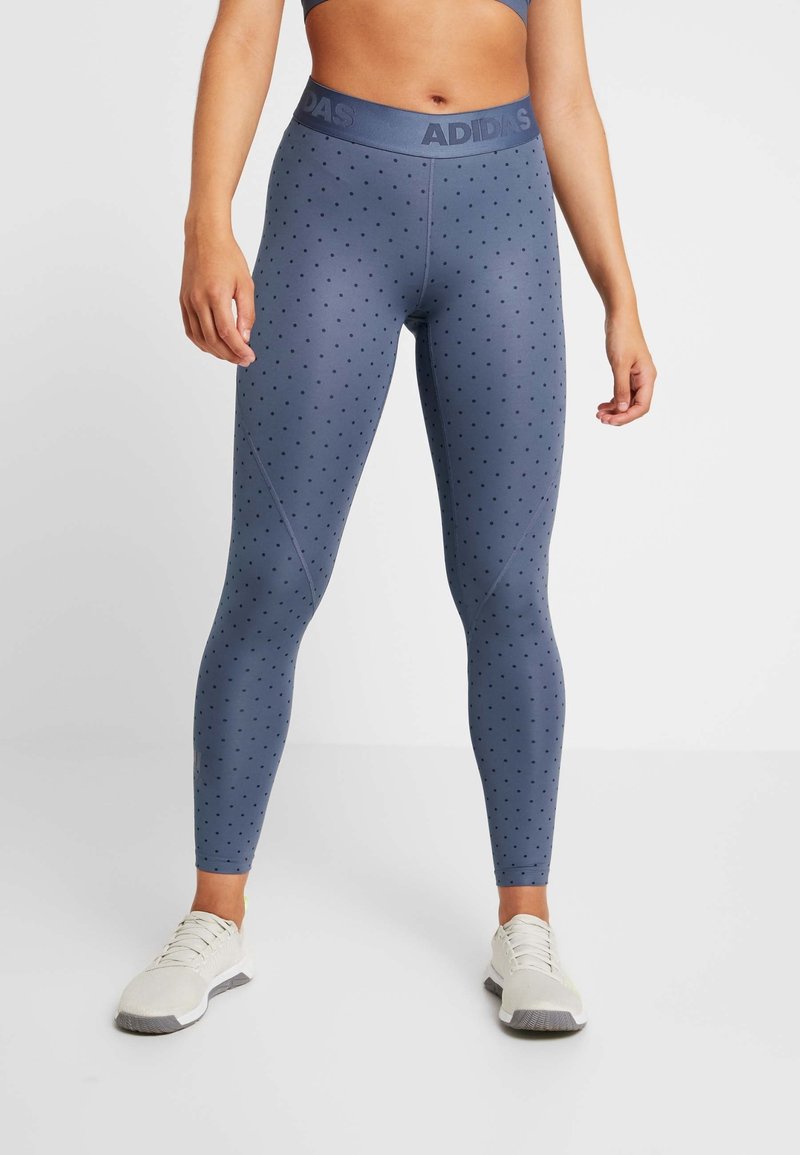 Granatowe legginsy w kropki, z szerokim elastycznym pasem oznaczonym "ADIDAS" i gładką, rozciągliwą fakturą.