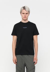 Zwarte katoenen t-shirt met korte mouwen, voorzien van een blauw geborduurd logo op de borst. Eenvoudig, klassiek passend ontwerp.
