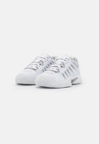 Pantofi sport albi cu un superior din plasă, accente texturate și trei dungi gri pe lateral. Concepuți cu o talpă căptușită pentru confort.