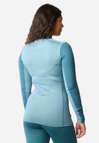 Long-sleeve active top in a gradient light blue shade, made from stretchy, smooth fabric with flat seams and a fitted design.