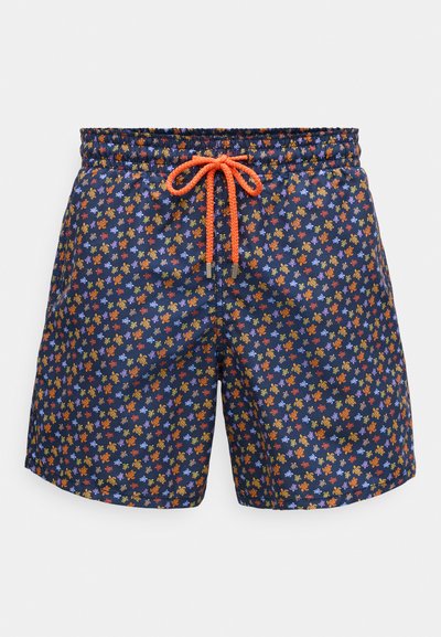 Pantaloni scurți de baie de culoare bleumarin cu imprimeu mic de țestoase colorate, talie elastică și șnur portocalie strălucitoare legat într-o fundă în centrul din față.
