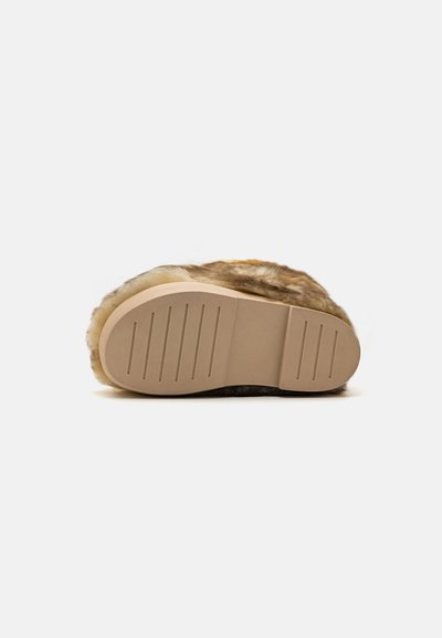 Chinelo forrado a pêlo castanho com sola de borracha texturizada em bege, apresentando sulcos horizontais para aderência e um design de bico arredondado.