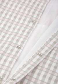 Tela de cuadros en gris y blanco con acentos en rosa, que presenta botones de presión plateados y un suave forro interior blanco.