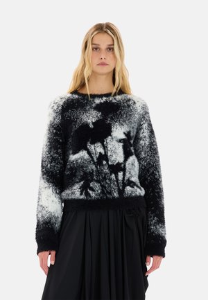 Maglione fuzzy bianco e nero con un motivo animale astratto, collo rotondo, maniche lunghe e orlo a coste. Texture morbida.
