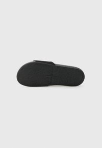 Black flip-flop sandal featuring a textured rubber sole and a cushioned strap with a logo detail. Flat design suitable for casual wear.