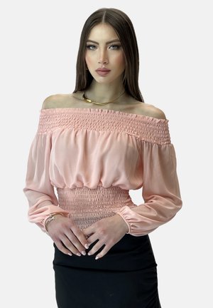 Blusa leggera color rosa pallido con spalline scoperte e dettagli arricciati in vita, maniche lunghe a sbuffo, abbinata a una gonna nera aderente.