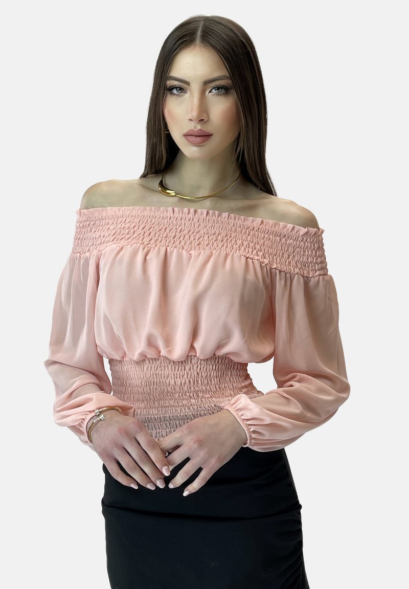 Off-the-shoulder, lyserød bluse med smocked detaljer ved taljen og lange, puffede ærmer, parret med en sort tætsiddende nederdel.