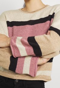 Maglione lavorato a maglia con righe orizzontali in beige, rosa e nero. Collo rotondo e vestibilità rilassata con tessuto testurizzato.