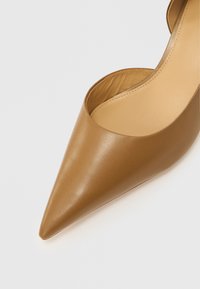 Tanfarvet læder højhælet sko med spids tå og udskårne sider. Glat tekstur med et minimalistisk design og ensfarvet finish.