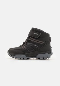 Black waterproof ankle boots with a rubber sole, Velcro strap, elastic laces, and textured fabric accents for stability and grip.