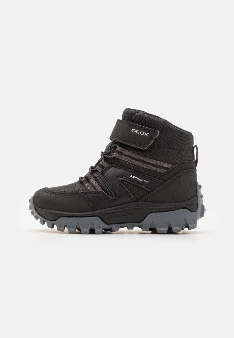 Black waterproof ankle boots with a rubber sole, Velcro strap, elastic laces, and textured fabric accents for stability and grip.