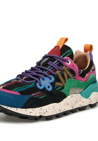 Baskets multicolores avec des lacets violets, semelle blanche éclaboussée, accents verts, bleus, roses et poignées orange sur la languette et le talon.