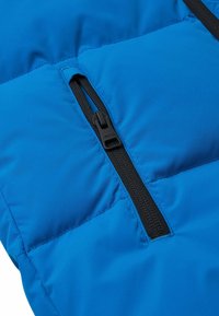 Sezione della giacca a piumino blu caratterizzata da una zip nera. Il tessuto è liscio e leggermente lucido, con sezioni trapuntate per l'isolamento.