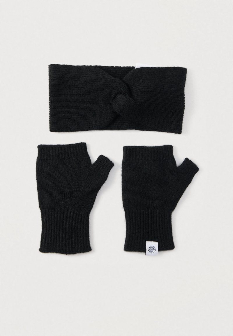 Crna pletena traka za glavu s čvorom iznad dvije odgovarajuće rukavice bez prstiju. Tkanina je rebrasta, mekana i rastezljiva.