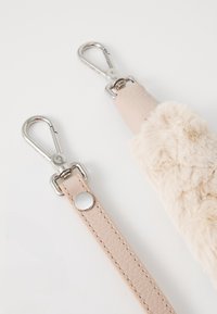 To beige lær reimer med sølv metallspenner, en reim glatt og pelsaktig, plassert på en hvit overflate.