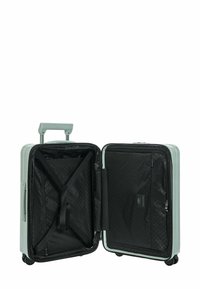 Valise rigide ouverte avec des compartiments intérieurs noirs, des sangles réglables, une poignée rétractable et quatre roues visibles sur fond blanc.