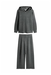 Grå strikket loungewear sæt, der har en hætte-top med en afslappet pasform og brede bukser, alt sammen lavet af blødt, tekstureret stof.
