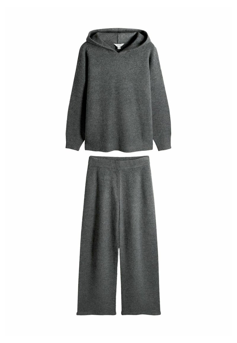 Grå strikket loungewear sæt, der har en hætte-top med en afslappet pasform og brede bukser, alt sammen lavet af blødt, tekstureret stof.