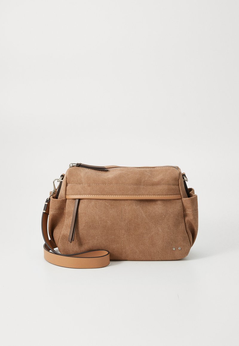 Sac bandoulière en daim marron clair avec une fermeture éclair, une poche avant et une sangle amovible. Présente des accents en cuir lisse et des coutures.