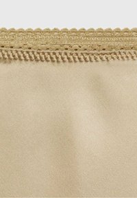 Tela beige con una textura suave y un borde decorativo de encaje en la parte superior, con bordes festoneados y sutiles detalles de costura.