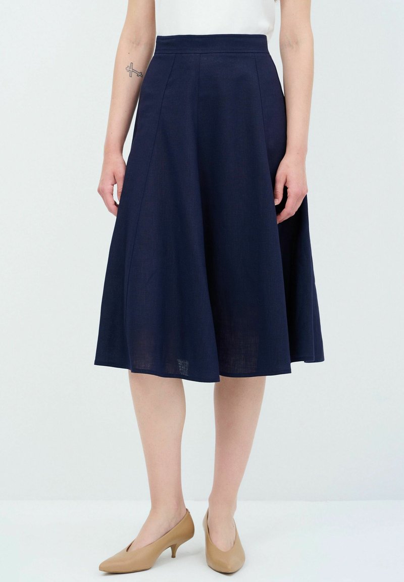 Gonna A-line color navy con una texture liscia, di lunghezza media, presenta una vita alta e dettagli sulle cuciture; abbinata a décolleté beige.