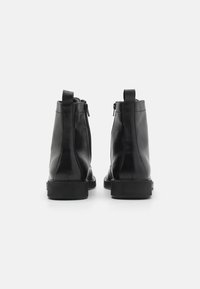 Bottines noires en cuir avec une finition lisse, zips latéraux, languettes et une semelle en caoutchouc texturé.