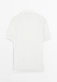 Polo shirt bianco a maniche corte con un tessuto testurizzato e un colletto classico. La parte posteriore presenta un motivo a rombi discreto.