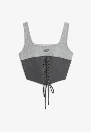 Grijze cropped top met een grijs jersey bovenstuk en een donkergrijze, gestructureerde onderkant. Voorzien van een vetersluiting aan de voorkant en metalen veterogen. Tekst op de borst.