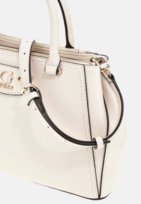 Borsa in pelle bianca con dettagli neri, caratterizzata da una forma strutturata, doppi manici, una tracolla removibile e hardware dorato.