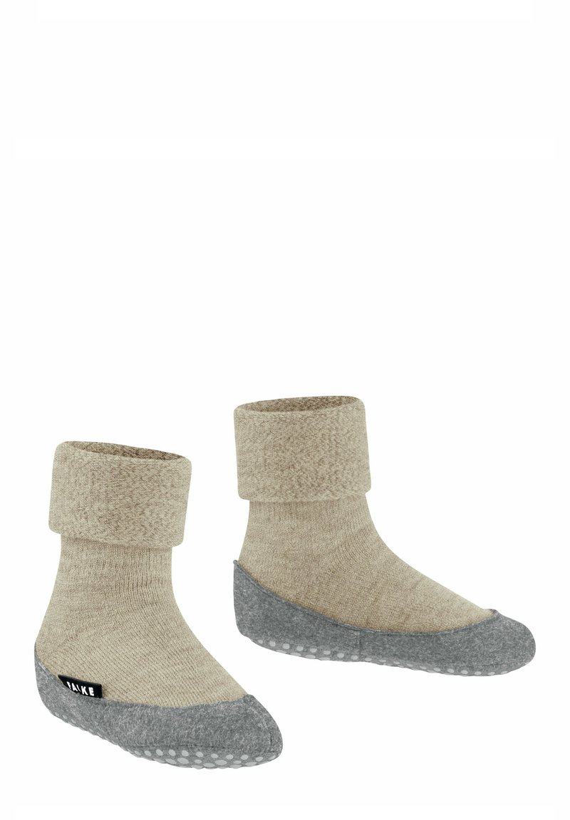 Calzini beige lavorati a maglia con risvolto e una suola grigia, texturizzata e antiscivolo, dotati di un'etichetta nera sul lato.