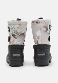 Botas con parte superior de tela gris claro que presenta estampados de conejitos, suelas de goma negras y correas ajustables para un ajuste seguro.
