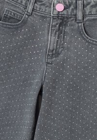 Jeans in denim grigio con un motivo a pois di borchie iridescenti. Bottone rosa in vita e design classico a cinque tasche.