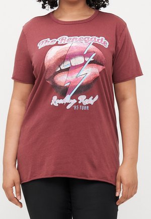 Bordowa koszulka z nadrukiem ust i błyskawicy oraz napisem "The Renegade Rocking Rebel '95 Tour", noszona przez osobę o kręconych włosach.