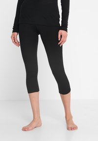 Schwarze Capri-Leggings aus leichtem, dehnbarem Stoff. Sie verfügen über eine glatte Oberfläche und eine enganliegende Passform, die bis zur Mitte der Waden reicht.