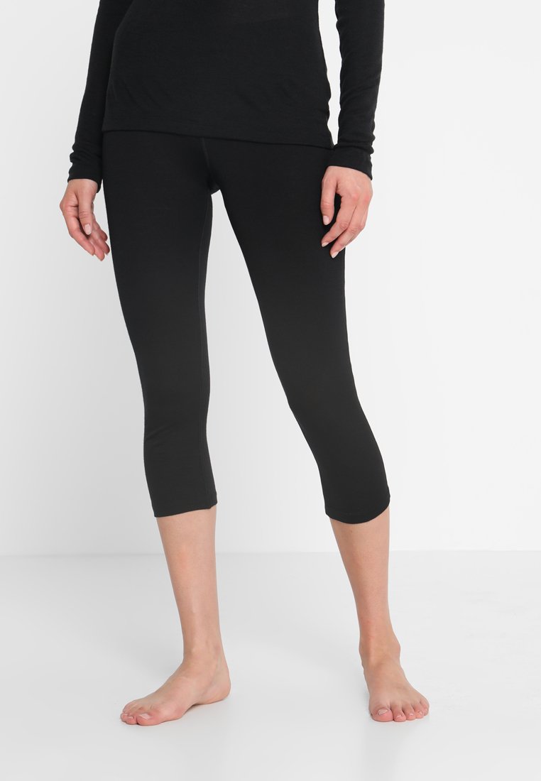 Schwarze Capri-Leggings aus leichtem, dehnbarem Stoff. Sie verfügen über eine glatte Oberfläche und eine enganliegende Passform, die bis zur Mitte der Waden reicht.