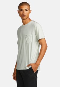 Lichtgroene crew-neck t-shirt van zacht materiaal, met een borstzak aan de linkerkant en subtiele stiksels op de schouders.
