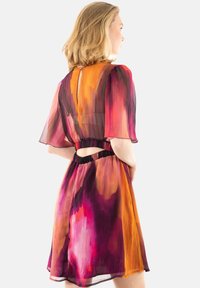 Vestido de manga corta en tejido translúcido con un patrón abstracto de acuarela en púrpura, rosa, naranja y negro; cintura elástica con detalle recortado.