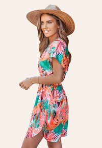 Abito floreale in tonalità vivaci di rosa, verde e arancione, con vita cintrata e maniche corte. Abbinato a un cappello di paglia a tesa larga.