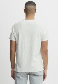 Lys grå, kortærmet t-shirt i et blødt, struktureret stof med rund hals og lige kant, vist fra ryggen.
