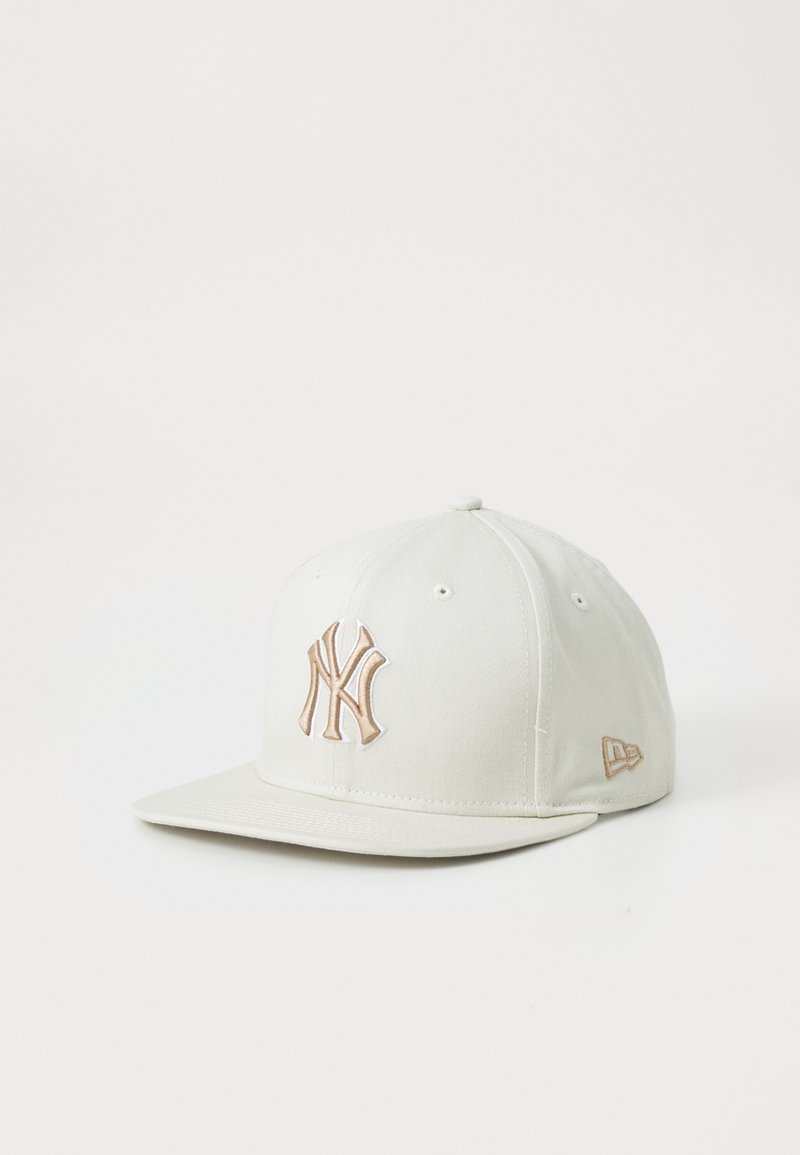 Casquette de baseball blanche avec logo New York Yankees beige brodé sur le devant et petit logo de marque beige sur le côté.