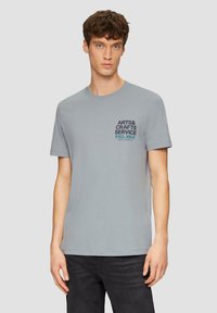 Grijze katoenen T-shirt met korte mouwen, voorzien van een blauwe bedrukte opdruk met de tekst "ARTS & CRAFTS SERVICE" en een rechte onderzoom.