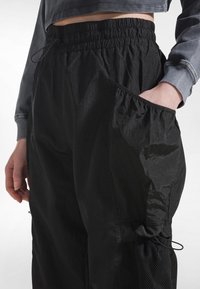 Sorte, lette cargobukser med elastisk talje, rynkede sidelommer og tekstureret mesh-detalje langs manchetterne.