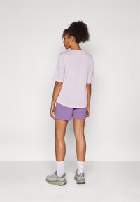 Light purple short-sleeve shirt with a scoop neck and back pleat, paired with purple shorts and gray sneakers. White ankle socks with pattern.