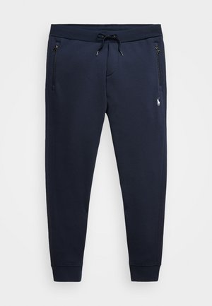 Pantalons de jogging bleu marine en mélange de coton doux, avec une taille ajustable, des poches zippées et un petit logo sur la cuisse gauche.