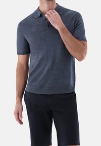 Námořnická modrá polo tričko s krátkým rukávem, límečkem, třemi knoflíčky a žebrovaným lemem. Vyrobeno z hladké, lehké látky.