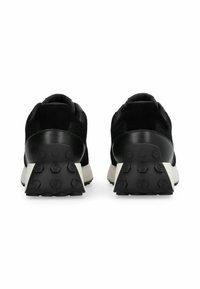 Chaussures de sport noires avec une tige en maille texturée, des accents en daim, et une semelle blanche épaisse présentant un motif hexagonal pour une meilleure adhérence.