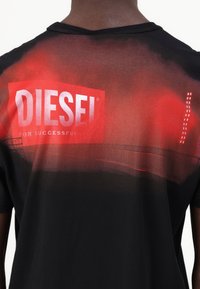 Juodas marškinėliai su raudonos spalvos gradientu, pereinančiu į juodą foną. Pagrindinis balto stačiakampio logotipas "DIESEL" ir tekstas "FOR SUCCESSFUL."
