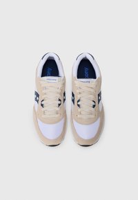Beige and white sneakers with mesh and suede materials, featuring a navy accent, round toe, and contrasting laces. Branding on the tongue.